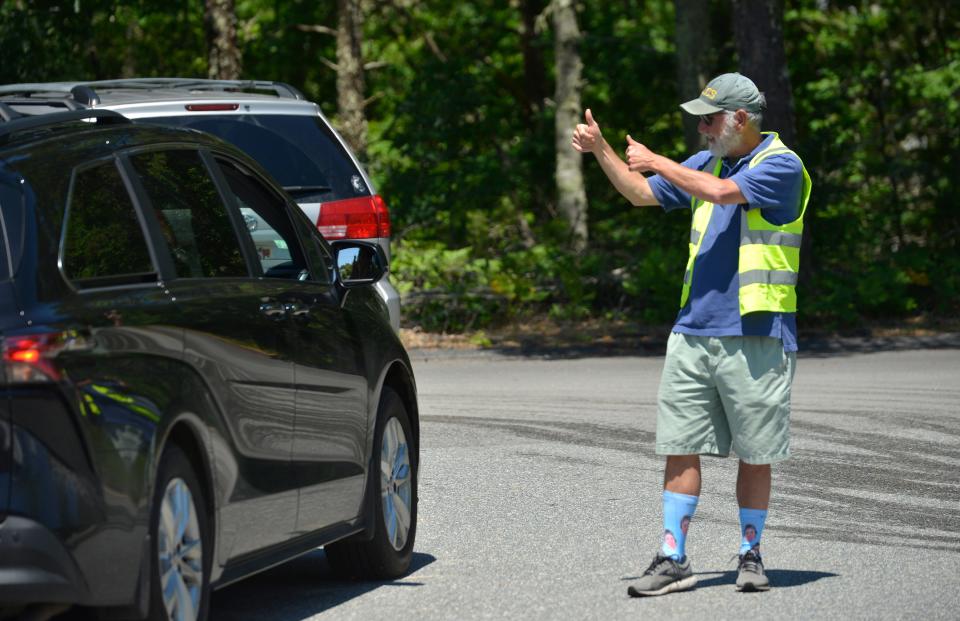 Cape Cod Lighthouse Charter School Executive Director Paul Niles, who is retiring, gives a student two thumbs up on Tuesday in Harwich as he helps direct the school buses and parent drivers on the last day of school for sixth- and seventh-graders.