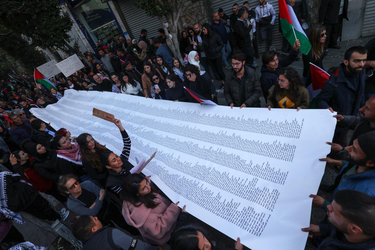 Palestinians carry a list of Gaza victims killed by Israel during a rally amid a general strike in Ramallah, a city in the West Bank.