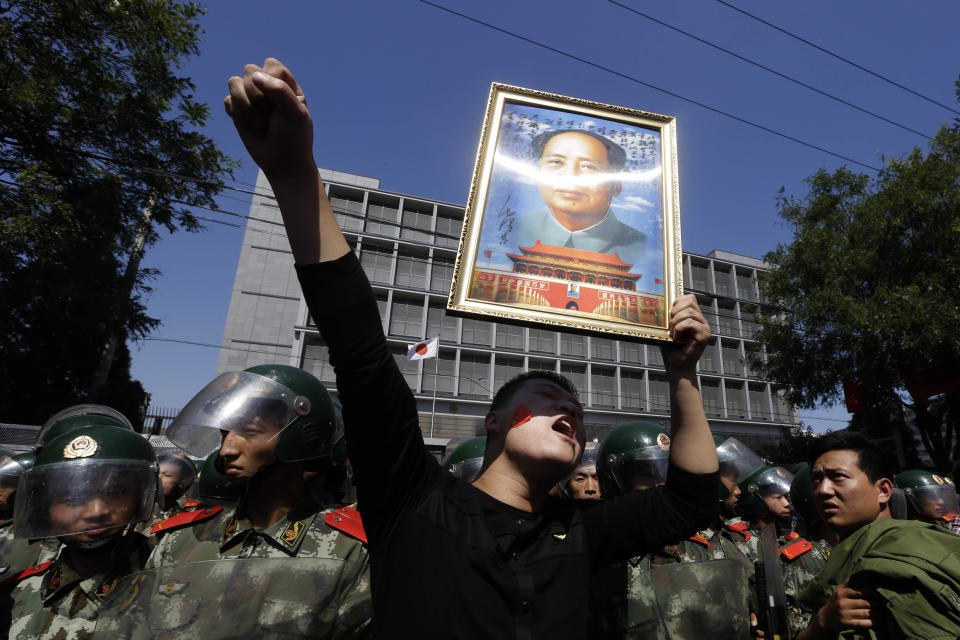 FILE - In this Sept. 15, 2012 file photo, a Chinese man holds up a portrait of former Chinese leader Mao Zedong during protests outside the Japanese Embassy in Beijing, China. The face of dissatisfaction with China’s Communist Party is the face of the man synonymous with it: Mao Zedong. Portraits of the revolutionary leader, hoisted by people born after his death 36 years ago, often led packs of demonstrators in protests over Japan’s effort last week to bolster its hold on islands claimed by China. (AP Photo/Ng Han Guan, File)