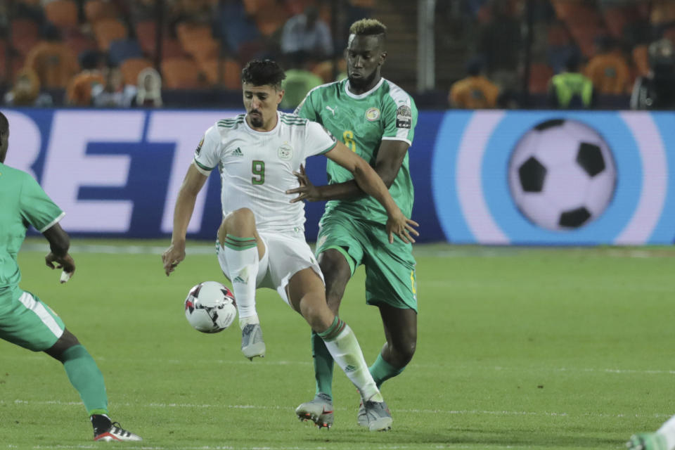Algeria's Baghdad Bounedjah, left, and Senegal's Salif Sane fight for the ball during the African Cup of Nations final soccer match between Algeria and Senegal in Cairo International stadium in Cairo, Egypt, Friday, July 19, 2019. (AP Photo/Hassan Ammar)