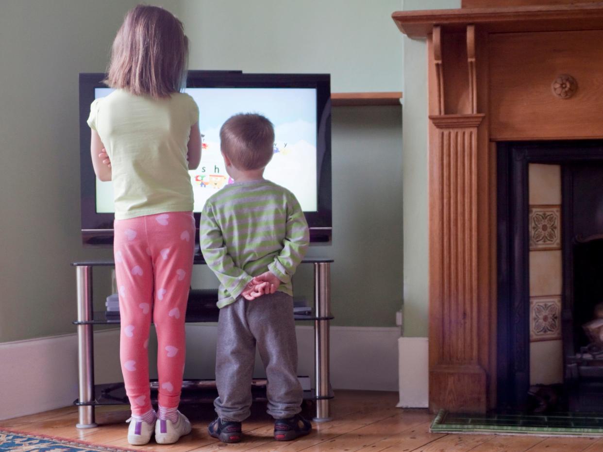 Two young children standing in front of a TV