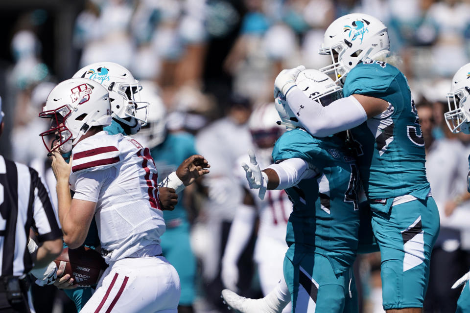 Coastal Carolina linebacker Myles Olufemi, middle, celebrates after sacking Massachusetts quarterback Brady Olson with linebacker Teddy Gallagher during the first half of an NCAA college football game on Saturday, Sept. 25, 2021, in Conway, S.C. (AP Photo/Chris Carlson)