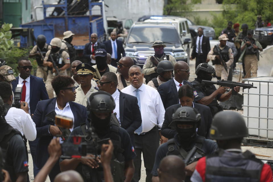 Haitian Prime Minister Garry Conille, center, and Police Chief Normil Rameau, center left, are surrounded by security as they arrive to the General Hospital in Port-au-Prince, Haiti, Tuesday, July 9, 2024. Authorities announced that police took control of the medical institution over the weekend from armed gangs. (AP Photo/Odelyn Joseph)