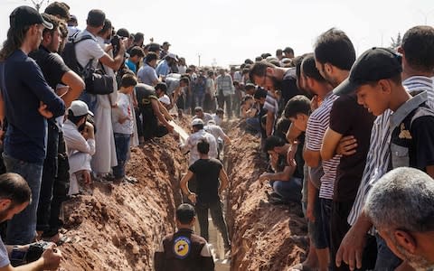 Members of the Syrian civil defence volunteers, also known as the White Helmets, bury their fellow comrades during a funeral in Sarmin, Idlib - Credit: AFP