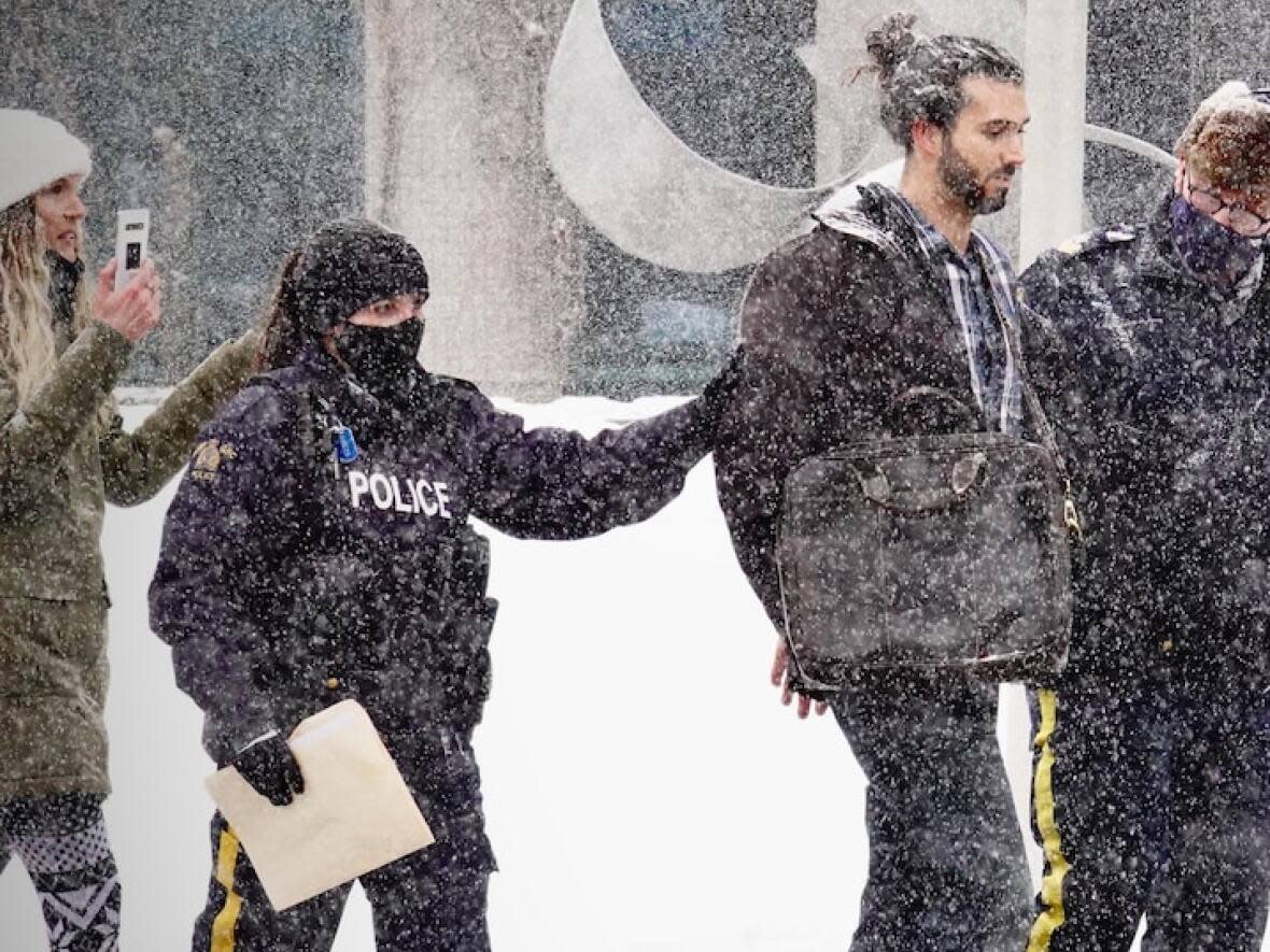 Britney Green, holding a phone, and Nicholas DeAngelis, as he was being taken into custody by RCMP on Jan. 24, 2021, outside Moncton city hall. (Guy LeBlanc/Radio-Canada - image credit)