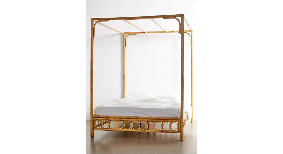 This canopy bed has a natural finish and caged paneling.