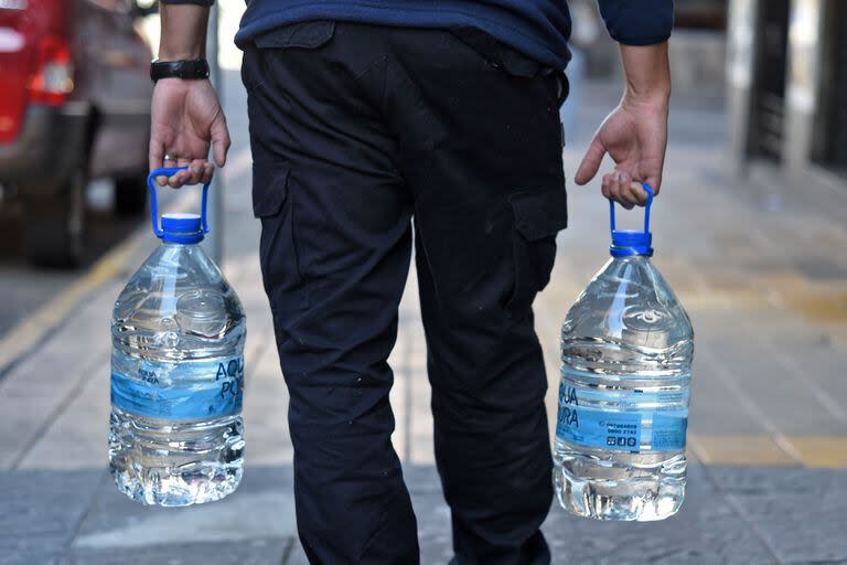 Un hombre lleva dos botellas de agua potable en Montevideo el 10 de julio de 2023, en medio de una severa sequía que provocó una crisis de agua en el país. 