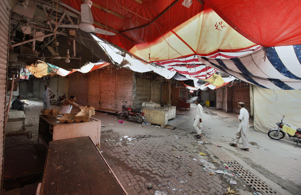 People walk through a main market which is closed due to a strike in Rawalpindi, Pakistan, Saturday, July 13, 2019. Pakistani traders have largely kept their business shut across the country against the new sales tax regime in the first budget of the new government they and opposition parties said came on the diktat of International Monetary Fund in turn of a $6bn bailout package. (AP Photo/Anjum Naveed)