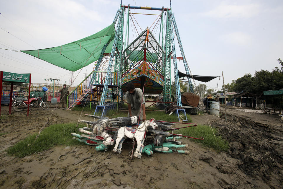 An amusement park worker collects a parts of a swinging horse ride after it was damaged by heavy rain, in Charsadda, Pakistan, Monday, Sept. 5, 2022. The U.N. refugee agency rushed in more desperately needed aid Monday to flood-stricken Pakistan as the nation's prime minister traveled to the south where rising waters of Lake Manchar pose a new threat. (AP Photo/Mohammad Sajjad)