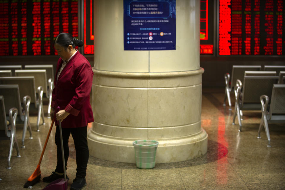 A cleaner sweeps the floor at a stock brokerage house in Beijing, Tuesday, Nov. 19, 2019. Asian shares were mixed Tuesday as investor sentiment remained cautious amid worries about the next development in trade talks between the United States and China. (AP Photo/Mark Schiefelbein)