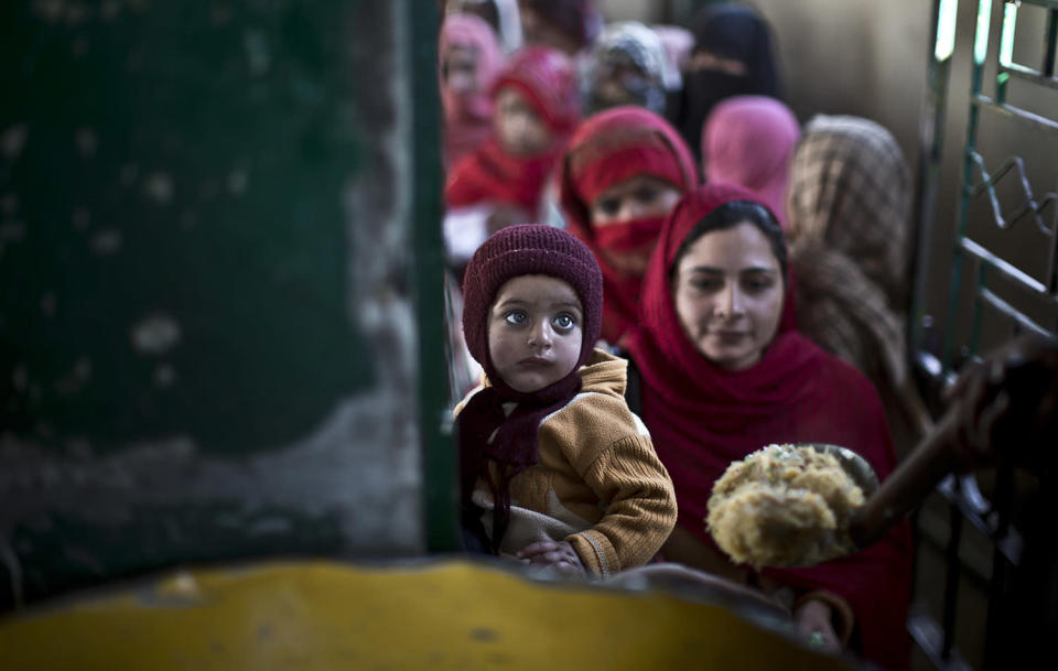 <p>A child is held by his mother as they wait to receive rice during a donated food distribution on the occasion of Prophet Mohammad’s birthday, at a shrine in Islamabad, Pakistan, Jan. 14, 2014. (Photo: Muhammed Muheisen/AP) </p>
