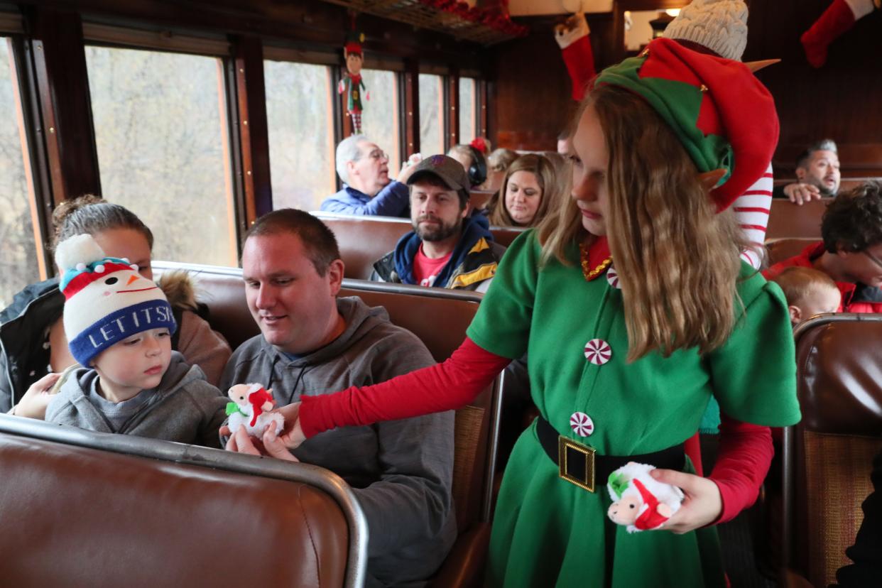 Hayden McCoy, 3, sitting with his parents David and Nina McCoy, gets a gift from elf Annika Romanowski, on the East Troy Railroad Museum Christmas Train in 2019. The Christmas Train, which departs from the depot in East Troy to "Santa's workshop" at the Elegant Farmer in Mukwonago, is again running weekends from Nov. 25 to Dec. 17, but tickets are again expected to sell out weeks ahead of time.