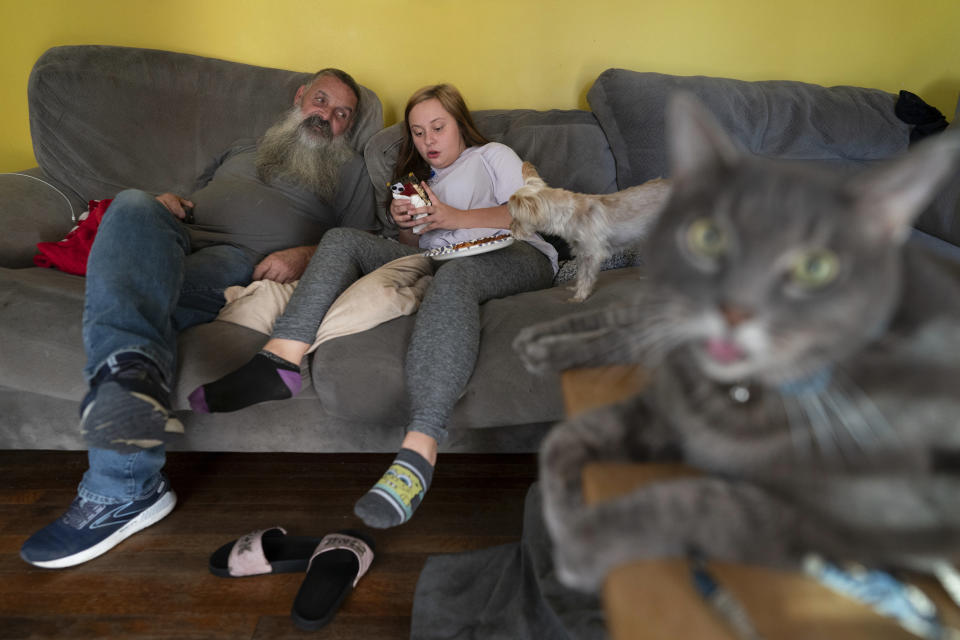 Joe Smith talks with his granddaughter Olivia in their home in Columbus, Ohio, Tuesday, Oct. 24, 2023, with their cat Marshall and dog Presley. Smith did not picture raising Olivia, but when his daughter's substance use disorder meant she couldn't care for her child, that's where Smith and his wife found themselves nineteen years ago. (AP Photo/Carolyn Kaster)