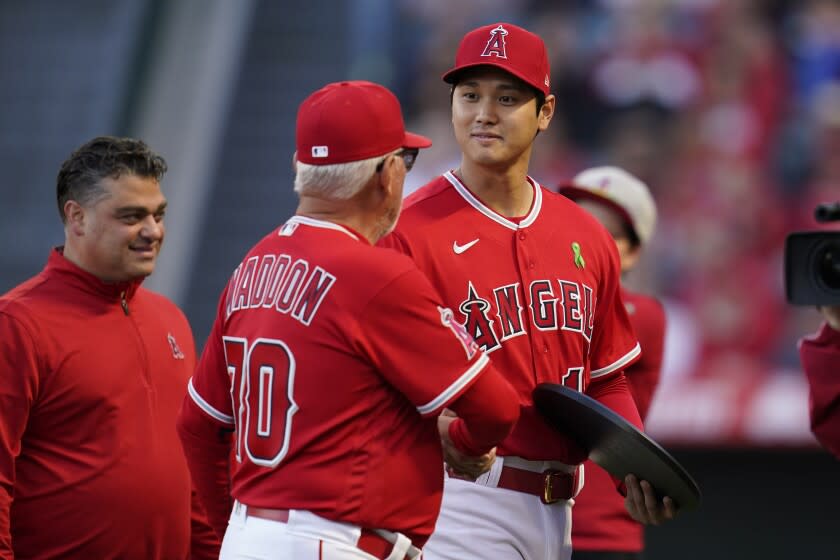 Shohei Ohtani, right, shakes hands with manager Joe Maddon. Angels general manager Perry Minasian is at left.