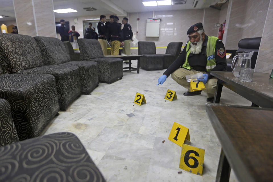 Police officers examine the crime scene following a shooting incident on the premises of the Peshawar High Court in Peshawar, Pakistan, Monday, Jan. 16, 2023. A man disguised as a lawyer shot and killed a prominent lawyer Abdul Latif Afridi on the court property in northwest Pakistan in an apparent case of an old enmity on Monday, police said. The attacker was quickly arrested. (AP Photo/Muhammad Sajjad)