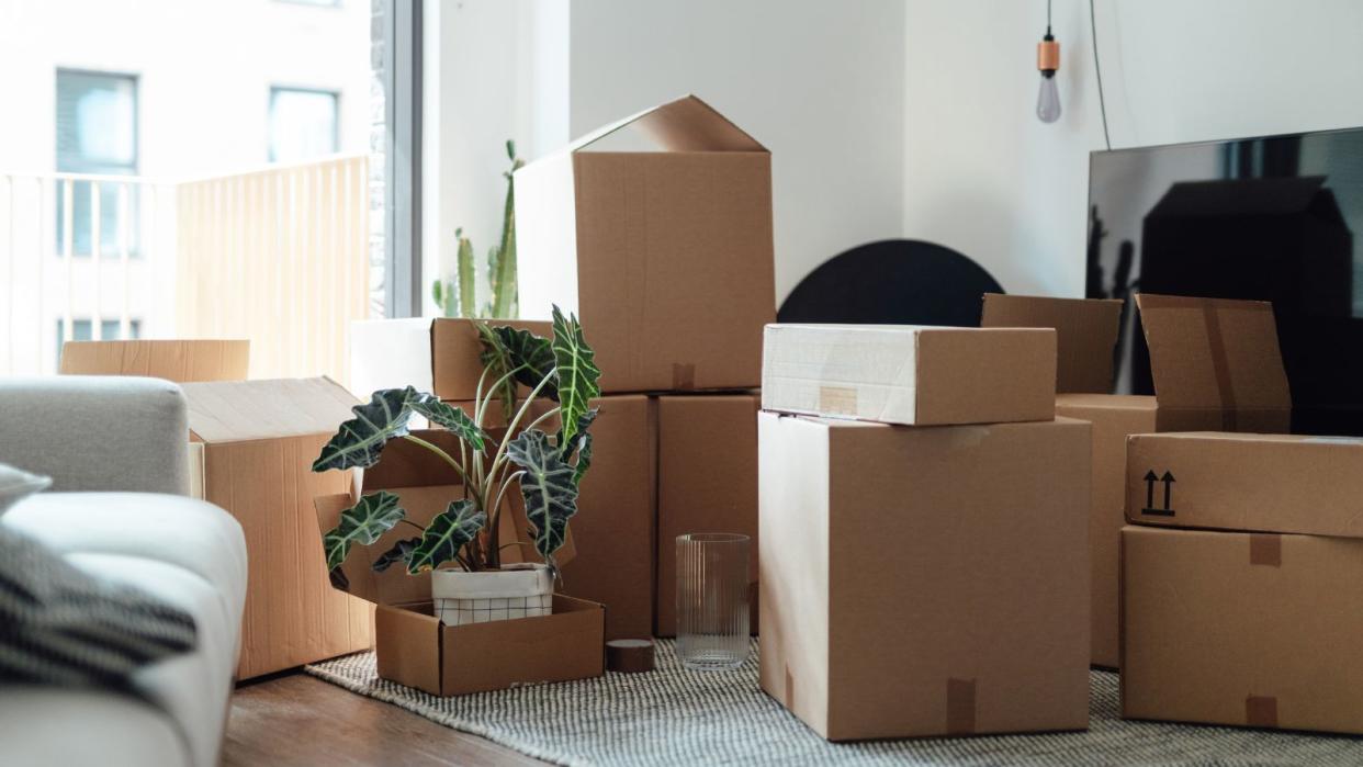  A room with a pile of moving boxes packed with belongings 