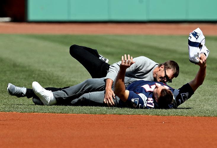 Rob Gronkowski is tackled by Tom Brady after stealing his jersey before Monday's opening day game between the Red Sox and Pirates at Fenway Park. (Getty Images)