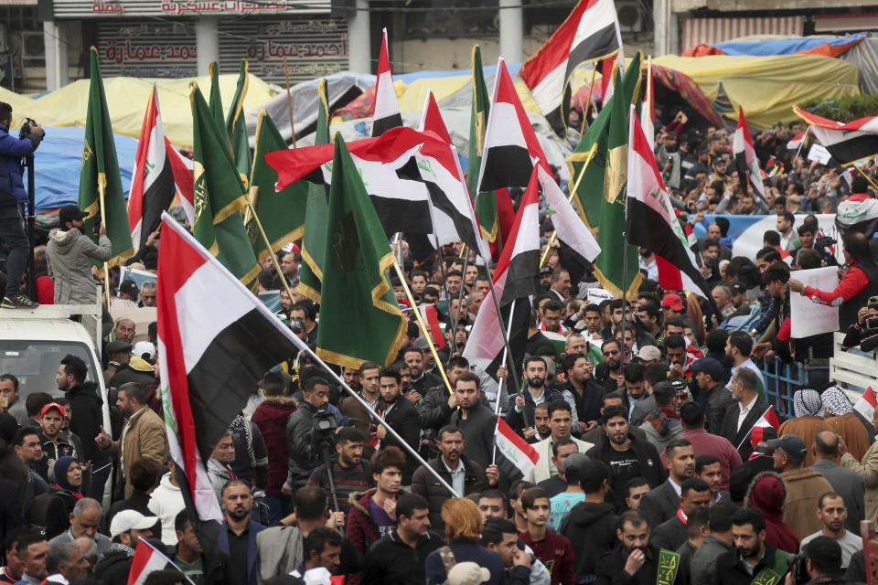 Protesters hold Popular Mobilization forces and Iraqi flags and chanting religious slogans march towards Tahrir Square in Baghdad, Iraq, Friday, Dec. 6, 2019. (AP Photo/Hadi Mizban)