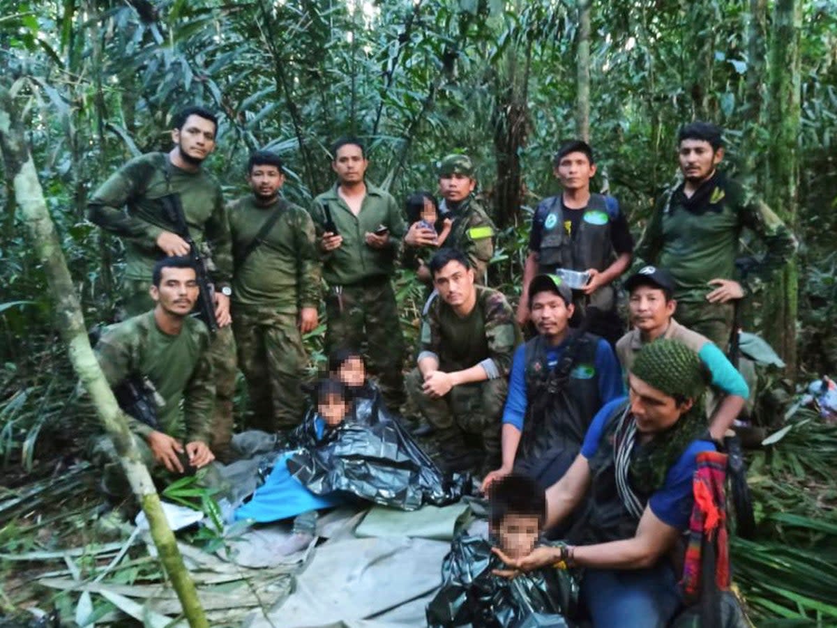 In this photo released by Colombia's Armed Forces Press Office, soldiers and Indigenous men pose for a photo with the four Indigenous children who were missing after a deadly plane crash, in the Solano jungle, Caqueta state, Colombia. (AP)