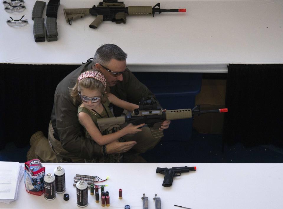 RNPS - PICTURES OF THE YEAR 2013 - A man shows a girl how to hold an airsoft gun during the NRA Youth Day at the National Rifle Association's annual meeting in Houston, Texas May 5, 2013. The National Rifle Association is showcasing women members and emphasizing that increasingly it's not just men who own firearms and oppose gun-control efforts. Female membership is up, the nation's leading advocate for gun ownership says, and its revamped website features profiles of "armed and fabulous" women and describes how women are bringing "new energy" to the NRA. REUTERS/Adrees Latif (UNITED STATES - Tags: POLITICS TPX)