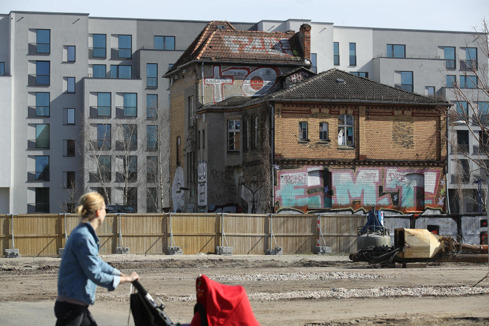 A woman pushes a pram as she walks past a pre-World War II house that stands next to new apartment buildings in a former industrial area on April 4, 2018 in Berlin, Germany. Photo: Sean Gallup/Getty Images