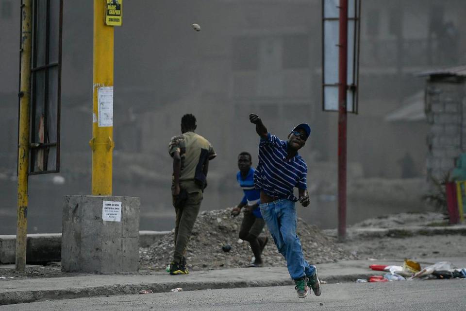 A protester demanding justice for the assassinated President Jovenel Moise hurls a stone in Cap-Haitien, Haiti, Thursday, July 22, 2021. Demonstrations after a memorial service for Moise turned violent on Thursday afternoon with protesters shooting into the air, throwing rocks and overturning heavy concrete barricades next to the seashore as businesses closed and people took cover.