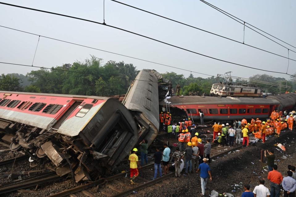 Rescue workers gather around damaged carriages during search for survivors at the accident site of a three-train collision near Balasore (AFP via Getty Images)