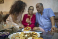 Yousra Sandabad and her parents, Moustafa and Afifa, video call their relatives as they enjoy Moroccan sweets on the first day of Eid in lockdown due to the Coronavirus pandemic, in Casablanca, Morocco, Sunday, May 24, 2020. (AP Photo/Mosa'ab Elshamy)