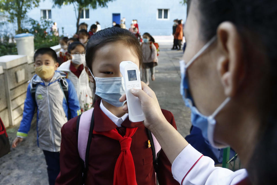 FILE - A teacher takes the body temperature of a schoolgirl to help curb the spread of the coronavirus before entering Kim Song Ju Primary School in Central District in Pyongyang, North Korea, Wednesday, Oct. 13, 2021. Before acknowledging domestic COVID-19 cases, Thursday, May 12, 2022, North Korea spent 2 1/2 years rejecting outside offers of vaccines and steadfastly claiming that its superior socialist system was protecting its 26 million people from “a malicious virus” that had killed millions around the world. (AP Photo/Cha Song Ho, File)