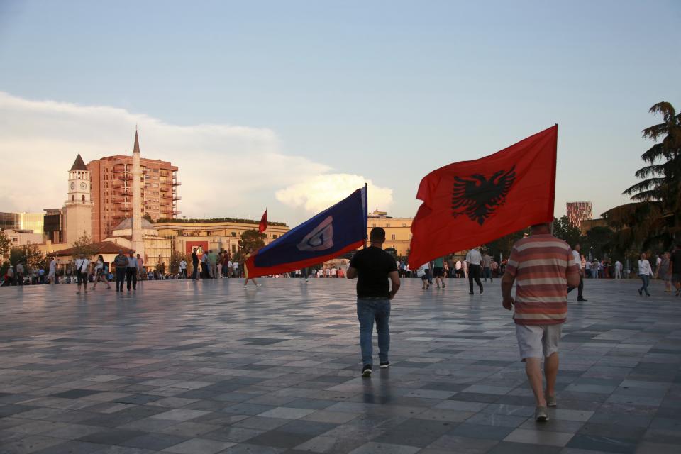 Antigovernment protesters hold an Albanian, right, and main opposition Democratic party flags during a rally at Skanderbeg square in Tirana, Friday, June 21, 2019. The opposition is boycotting the local elections planned for June 30 and has threatened to disrupt them.(AP Photo/Hektor Pustina)