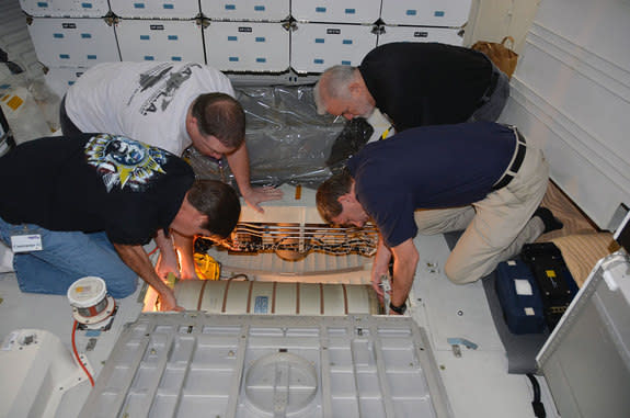 NASA workers lower a waste water tank below the crew cabin of the space shuttle Endeavour at the California Science Center in Los Angeles.