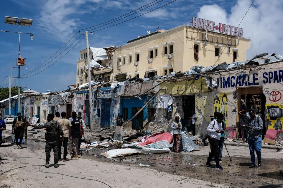 Media report in front of destored building after a deadly 30-hour siege by Al-Shabaab jihadists at Hayat Hotel in Mogadishu on August 21, 2022. - At least 13 civilians lost their lives and dozens were wounded in the gun and bomb attack by the Al-Qaeda-linked group that began on Friday evening and lasted over a day, leaving many feared trapped inside the popular Hayat Hotel.