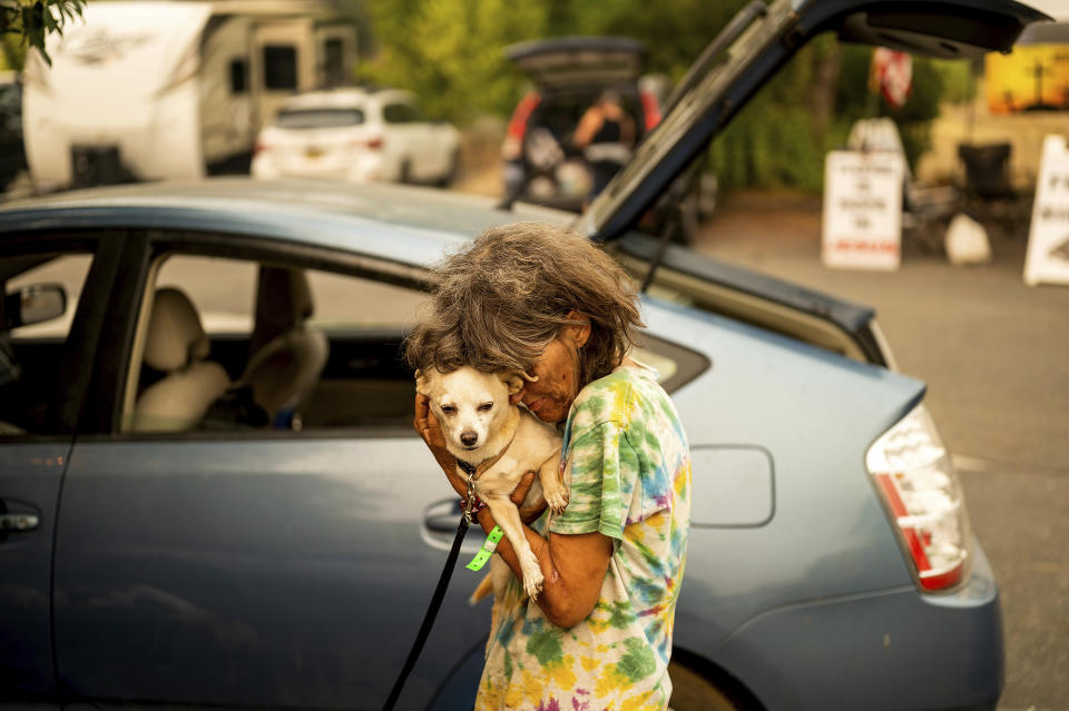Linda Hance, who evacuated from her home near Foresthill, hugs her dog Amigo outside a shelter for Mosquito Fire evacuees in Auburn, Calif., on Friday, Sept. 9, 2022. (AP Photo/Noah Berger)