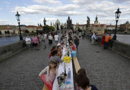 FILE - In this Tuesday, June 30, 2020 file photo, residents sit to dine on a 500 meter long table set on the medieval Charles Bridge, after restrictions were eased following the coronavirus pandemic in Prague, Czech Republic. Weeks after the citizens of Prague said a symbolic farewell to the coronavirus, the second wave has struck hard and the number of confirmed cases is setting new records almost daily. It is currently at a similar level to its neighbor German, which has a population eight times the size. The health minister has announced new restrictions, including closing bars, restaurants and clubs at midnight and making it mandatory to wear masks in all spaces in schools. (AP Photo/Petr David Josek, File)