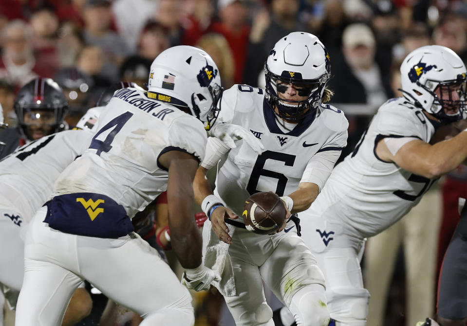 West Virginia quarterback Garrett Greene (6) hands off the ball to West Virginia running back CJ Donaldson Jr. (4) on a play against Oklahoma during the first half of an NCAA college football game Saturday, Nov. 11, 2023, in Norman, Okla. (AP Photo/Alonzo Adams)