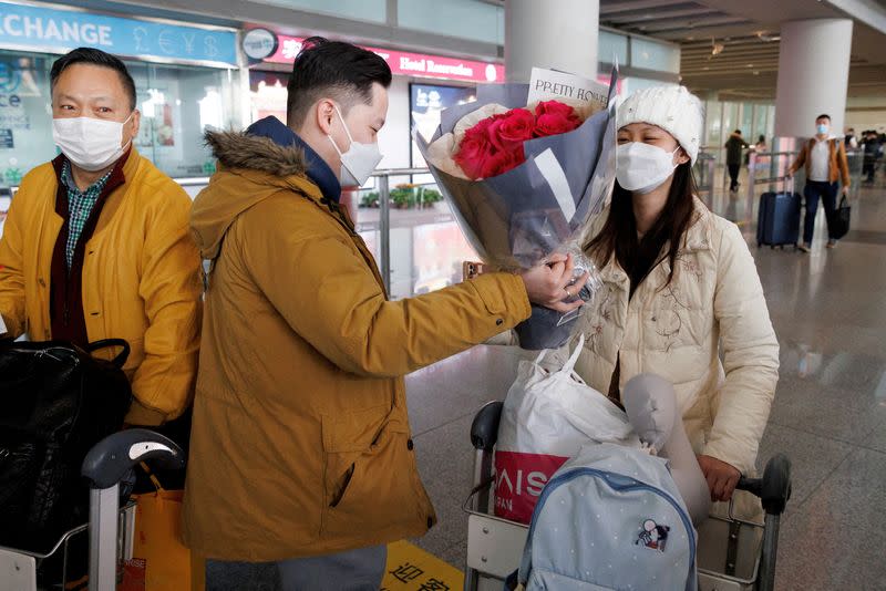 FILE PHOTO: A man hands flowers to a woman after she came through the international arrivals gate at Beijing Capital International Airport after China lifted the COVID-19 quarantine requirement for inbound travellers in Beijing