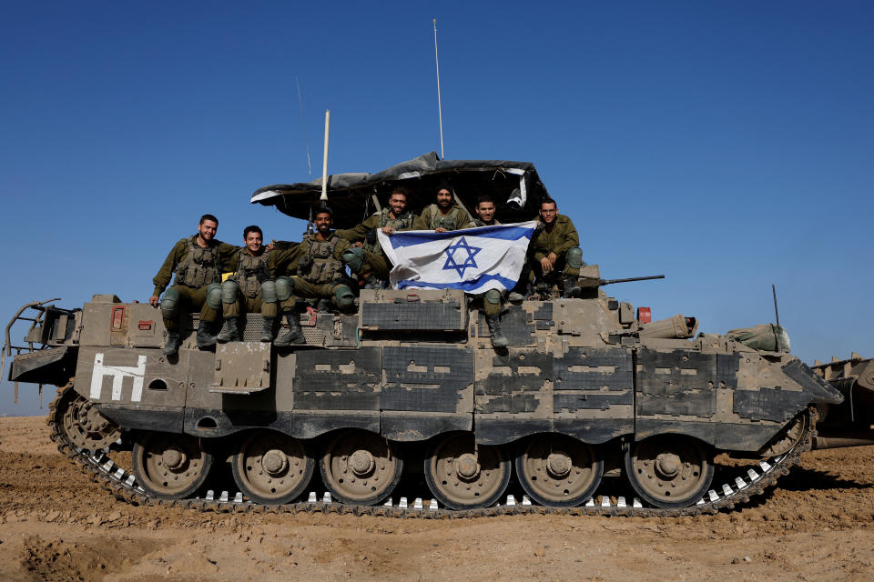 巴勒斯坦伊斯蘭組織哈瑪斯和以色列暫時休戰期間，以色列士兵從加薩返回後，在以色列邊境附近的一輛軍車上舉著國旗。（路透社）