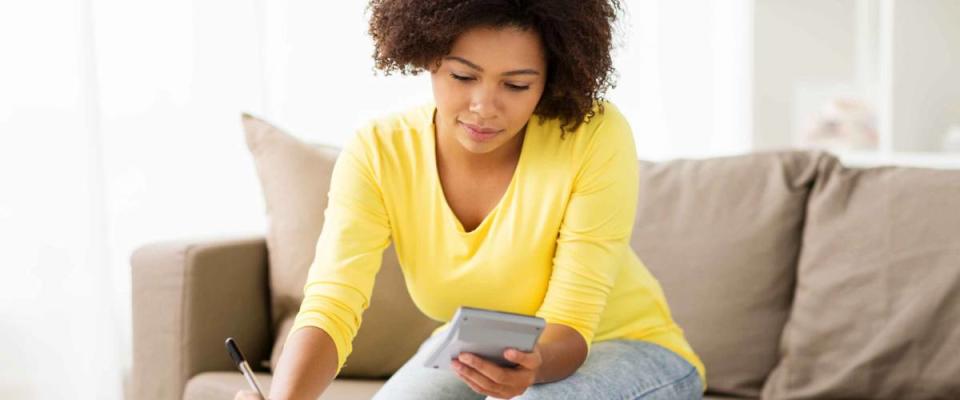 budget, finances and people concept - african american woman with papers and calculator counting money at home