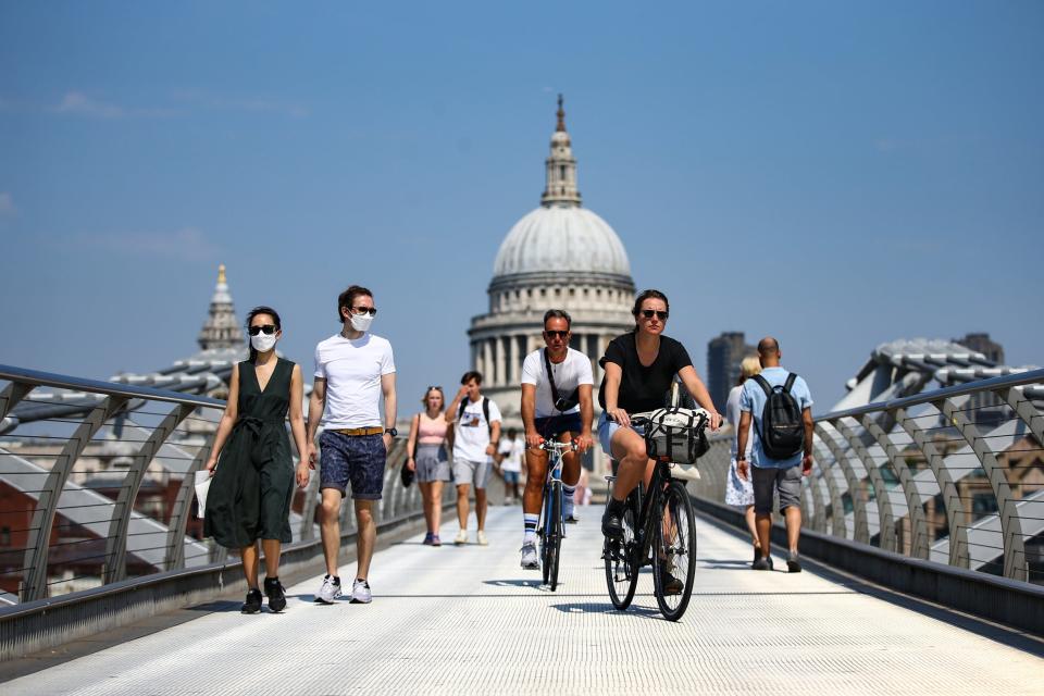 People wearing faces mask cross the Millennium Bridge in London (Getty Images)