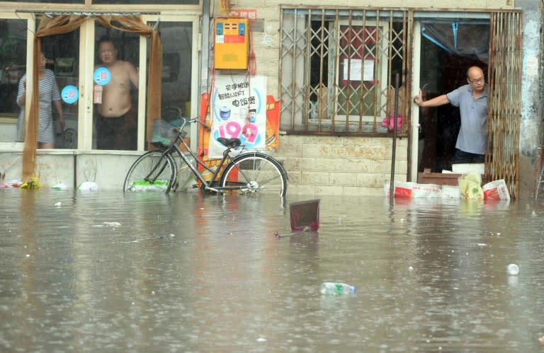 Chinese residents look at a flooded area caused by heavy rain in Beijing on July 20, 2016