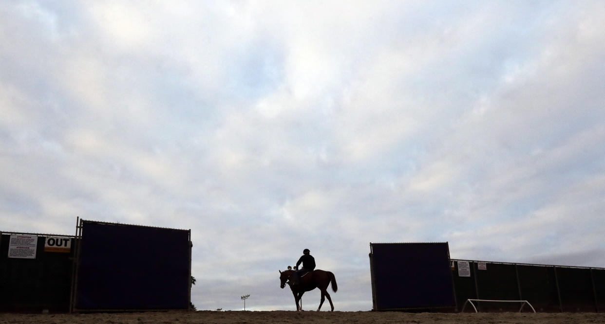 A horse and rider make their way onto the track during morning workouts before the Breeders Cup horse races Wednesday, Nov. 1, 2017, in Del Mar, Calif. Del Mar is hosting the $28 million, 13-race Breeders' Cup for the first time. The season-ending championships open with four races on Friday followed by nine, including the Classic, on Saturday. (AP Photo/Gregory Bull)