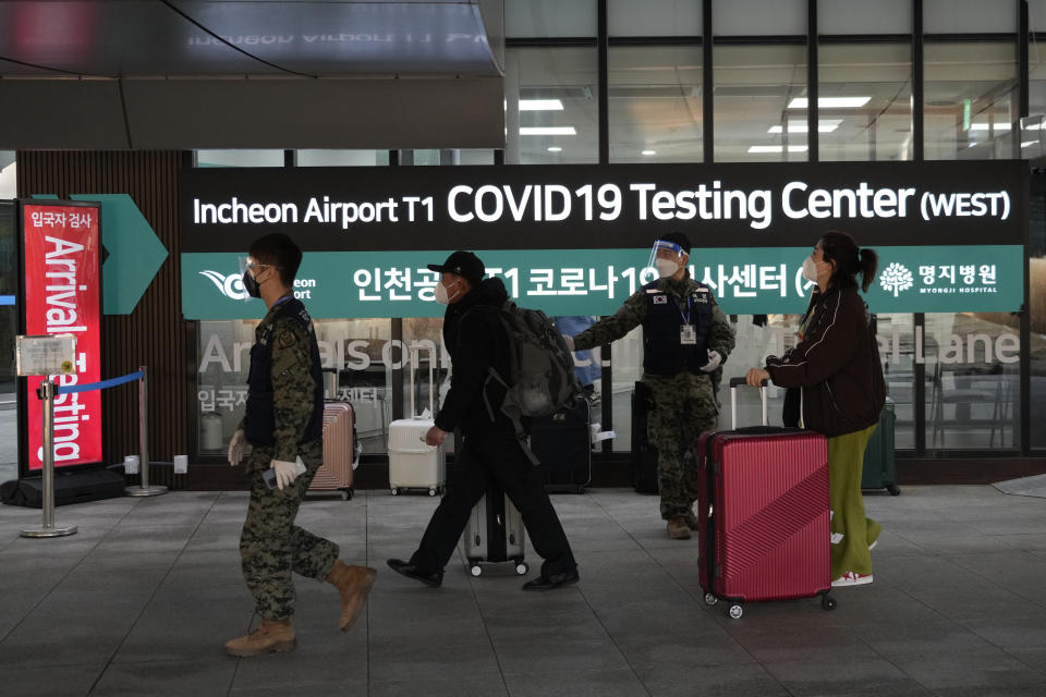 Passengers arriving from China pass by a COVID-19 testing center at the Incheon International Airport in Incheon, South Korea, Tuesday, Jan. 10, 2023. China suspended visas Tuesday for South Koreans to come to the country for tourism or business in apparent retaliation for COVID-19 testing requirements on Chinese travelers. (AP Photo/Ahn Young-joon)