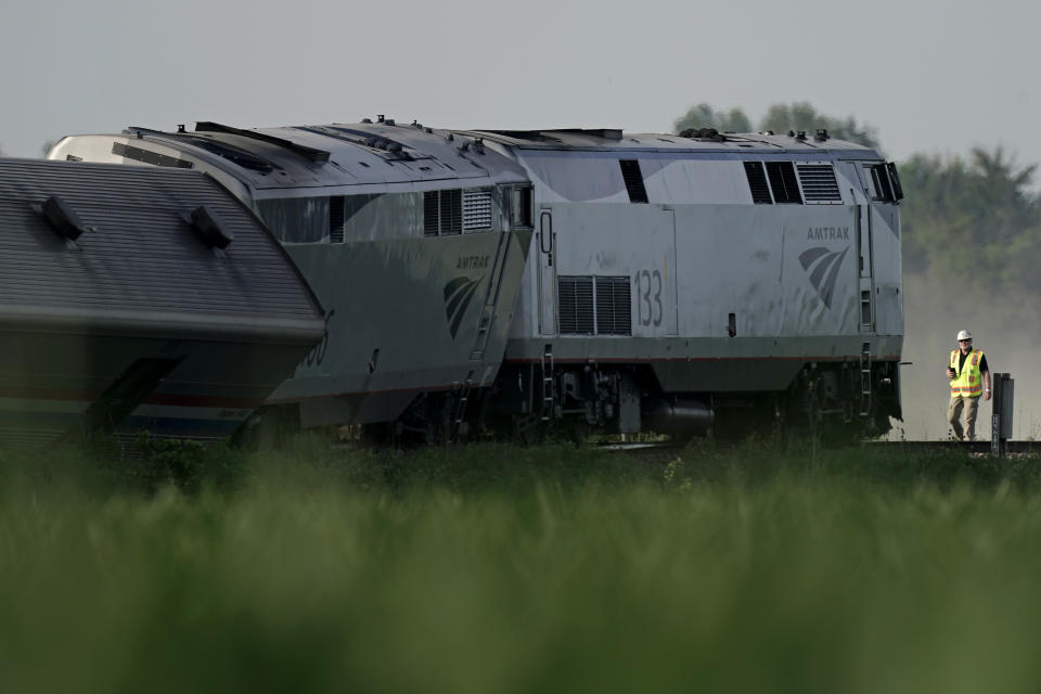 A worker inspects the scene of an Amtrak train which derailed after striking a dump truck, Monday, June 27, 2022, near Mendon, Mo. (AP Photo/Charlie Riedel)