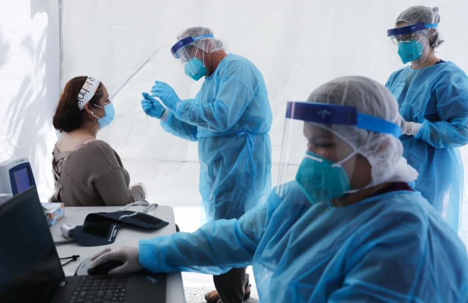 Healthcare workers prepare to test a woman at a mobile clinic in Los Angeles, California, on 15 July.