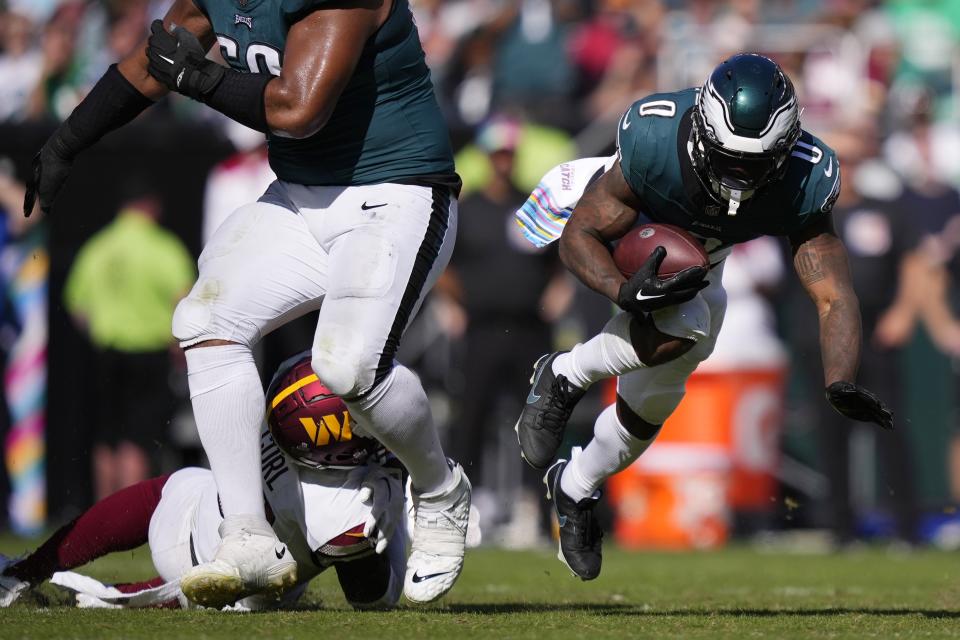 Philadelphia Eagles running back D'Andre Swift (0) falls with the ball near Washington Commanders safety Kamren Curl during the second half of an NFL football game Sunday, Oct. 1, 2023, in Philadelphia. (AP Photo/Matt Slocum)