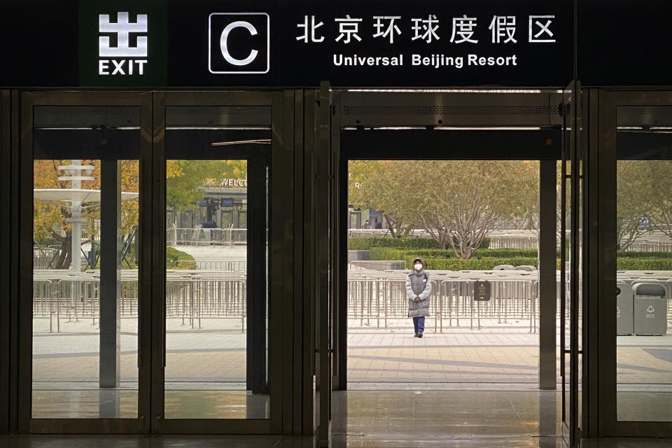 A worker wearing a face mask stands outside an exit from a subway station to stop visitors from going to the Universal Studios Beijing resort, which according to a notice was closed for epidemic control, in Beijing, Wednesday, Oct. 26, 2022. The Chinese city of Shanghai started administering an inhalable COVID-19 vaccine on Wednesday in what appears to be a world first. (AP Photo/Mark Schiefelbein)