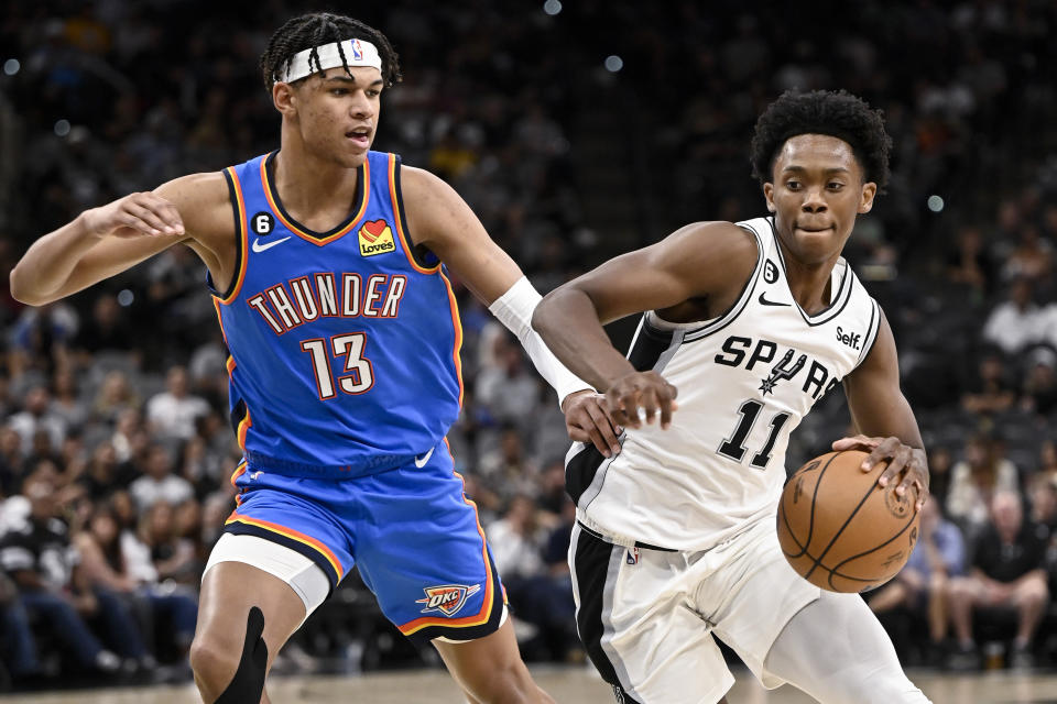 San Antonio Spurs' Josh Primo (11) drives against Oklahoma City Thunder's Ousmane Dieng during the second half of a preseason NBA basketball game Thursday, Oct. 13, 2022, in San Antonio. Oklahoma City won 118-112. (AP Photo/Darren Abate)