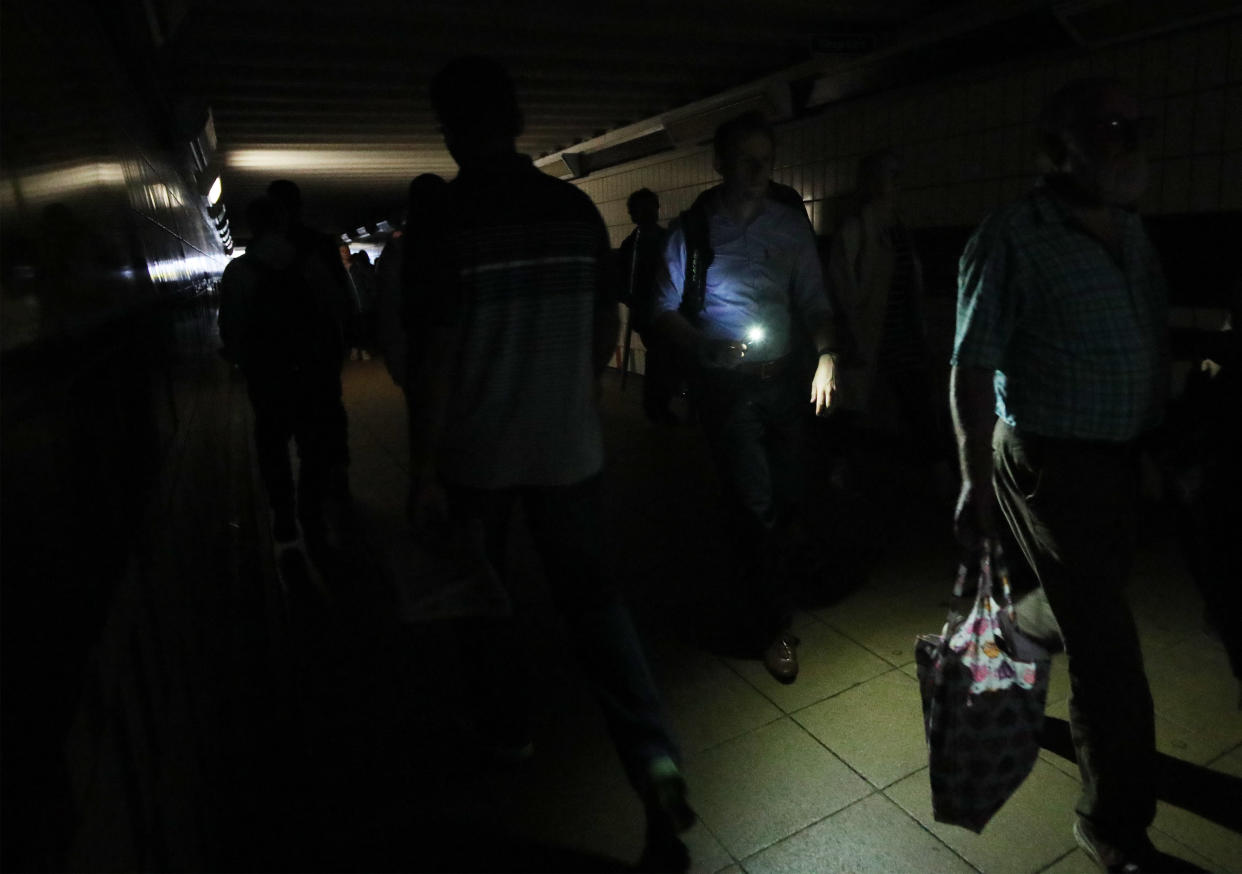 People walking in complete darkness at Clapham Junction station in London during a power cut, which has caused �apocalyptic� rush-hour scenes across England and Wales, with traffic lights down and trains coming to a standstill.