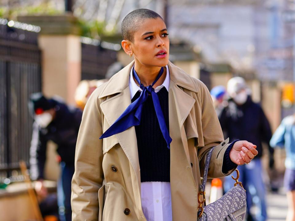 Actress Jordan Alexander wears a trench coat, handkerchief, and Dior purse on the streets of New York City.