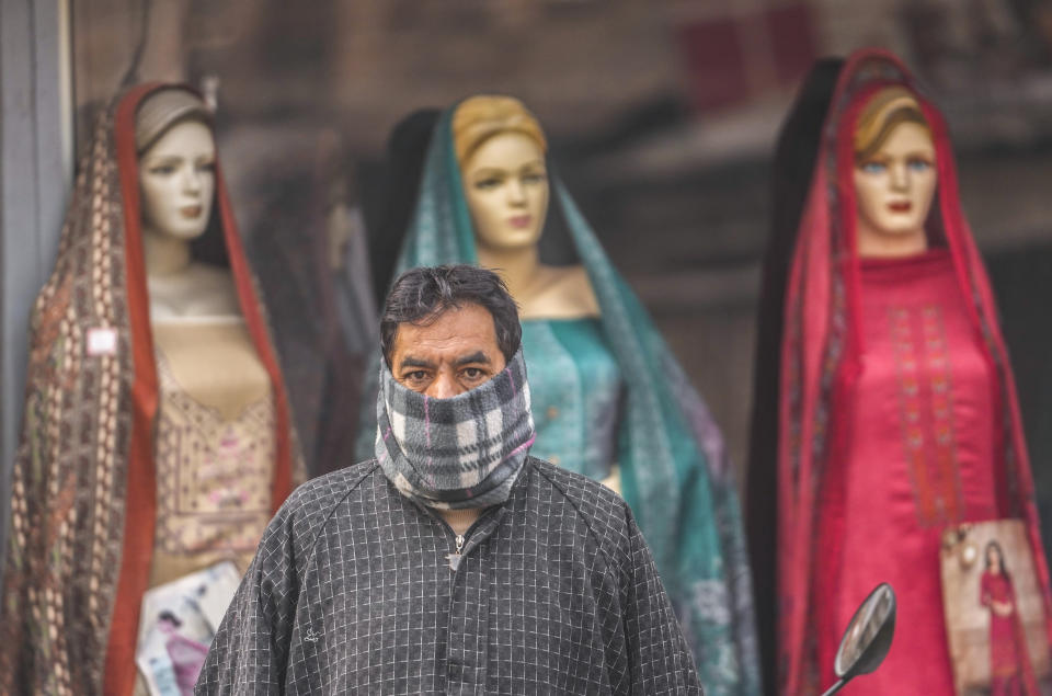 A man has his face covered in woolen cloth as he awaits transport in front of a clothes shop on a cold day in Srinagar, Indian controlled Kashmir, Monday, Dec. 11, 2023. India’s top court on Monday upheld a 2019 decision by Prime Minister Narendra Modi’s government to strip disputed Jammu and Kashmir’s special status as a semi-autonomous region with a separate constitution and inherited protections on land and jobs. (AP Photo/Mukhtar Khan)